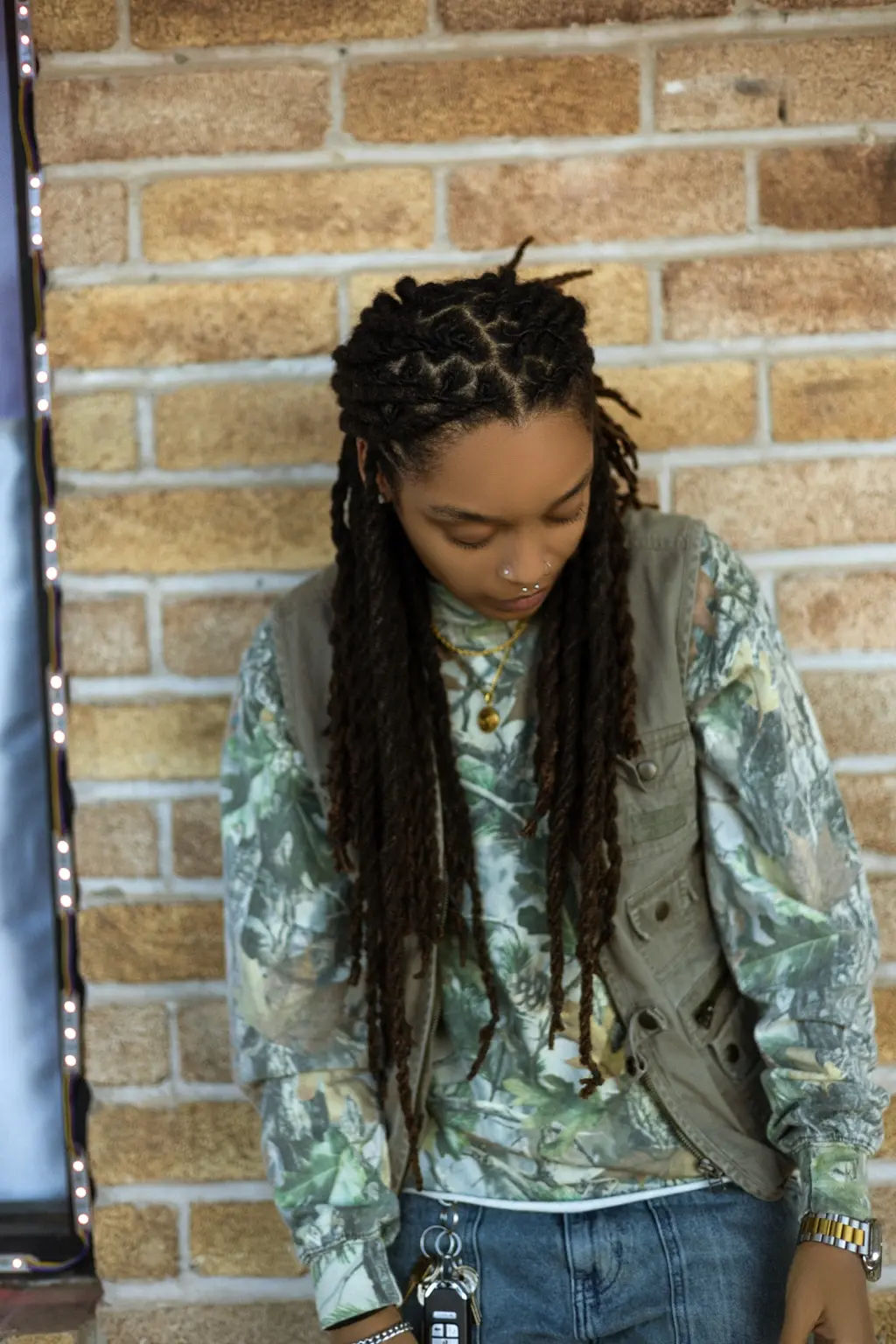 Camo layered look against a brick wall